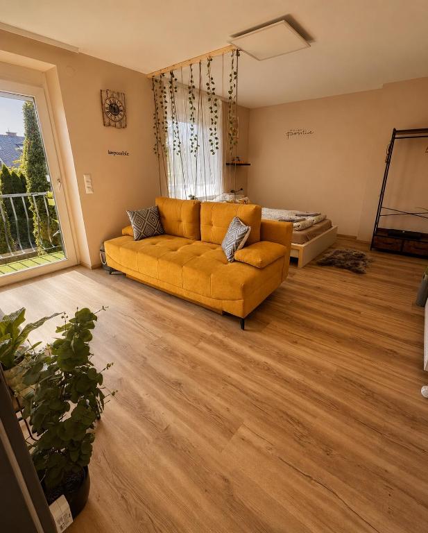 a living room with a yellow couch and a large window at Smile Home in Klagenfurt