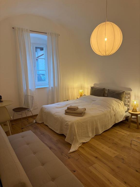 a bedroom with a large white bed and a chandelier at room4you Lambach Apartment, Studiozimmer & Zimmer in Lambach