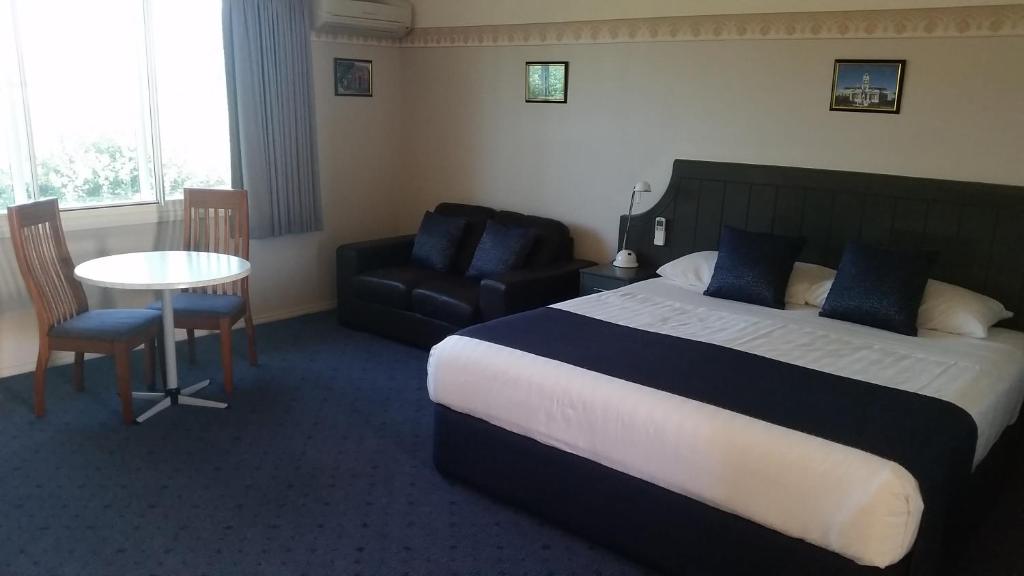 um quarto de hotel com uma cama, uma cadeira e uma mesa em Ararat Southern Cross Motor Inn em Ararat