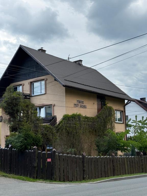 a house with a black roof behind a fence at Pokoje Przy Szlaku Agroturystyka in Żabnica
