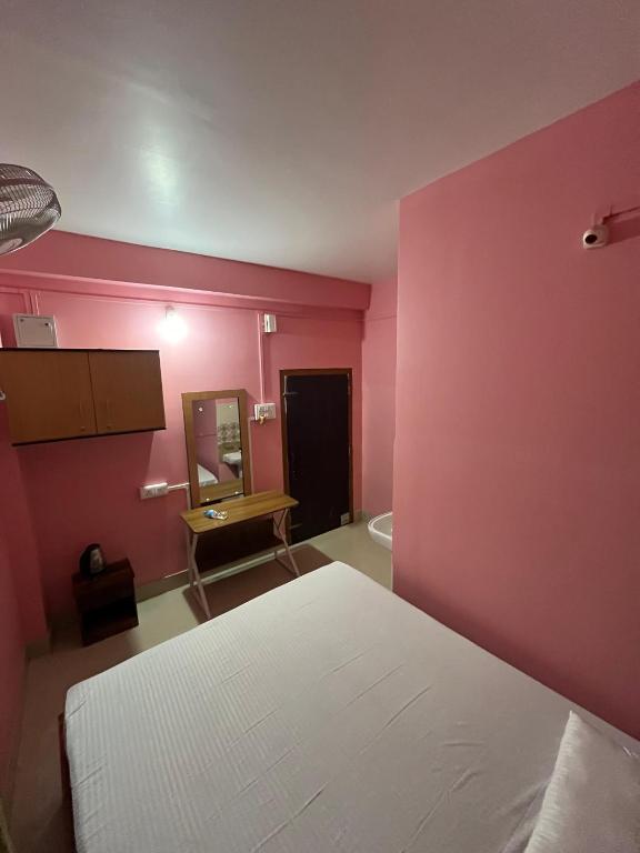 a pink room with a bed and a mirror at Hotel Diyo inn in Guwahati