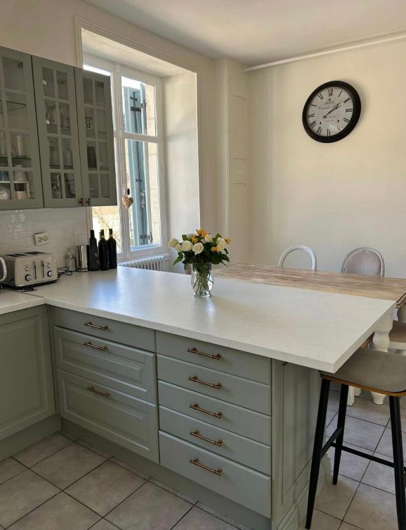 a kitchen with a counter with a clock on the wall at Le clos joli in Saint-Saviol