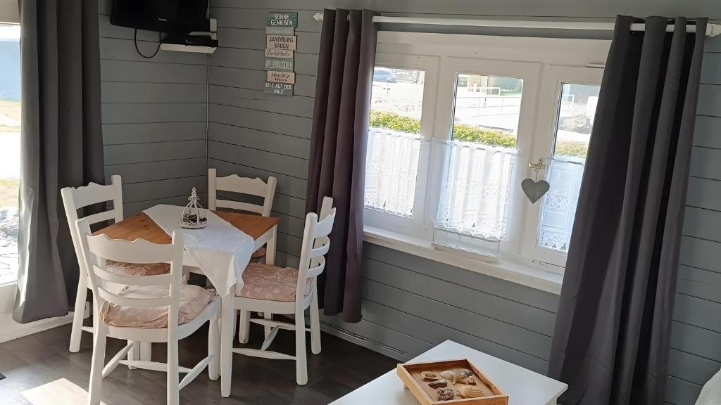 a dining room with a table and chairs and a window at Glücks-Gezeiten in Wurster Nordseeküste