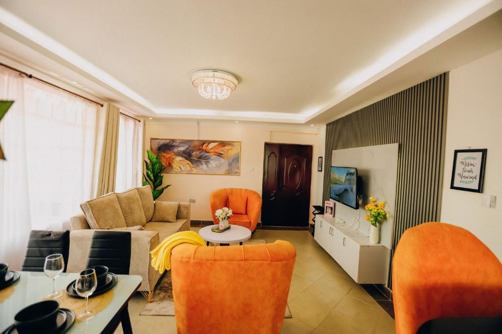 a living room with a couch and orange chairs at Rouse precious haven in Nakuru
