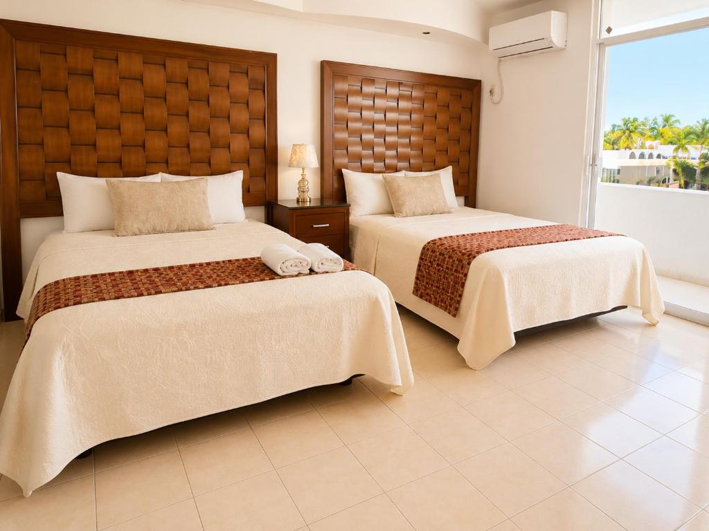 a bedroom with two beds and a large window at Zona Dorada Living in Mazatlán
