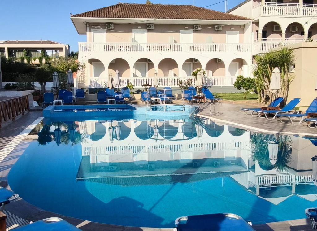 a pool in front of a hotel with blue chairs at Ragias Studios in Tsilivi