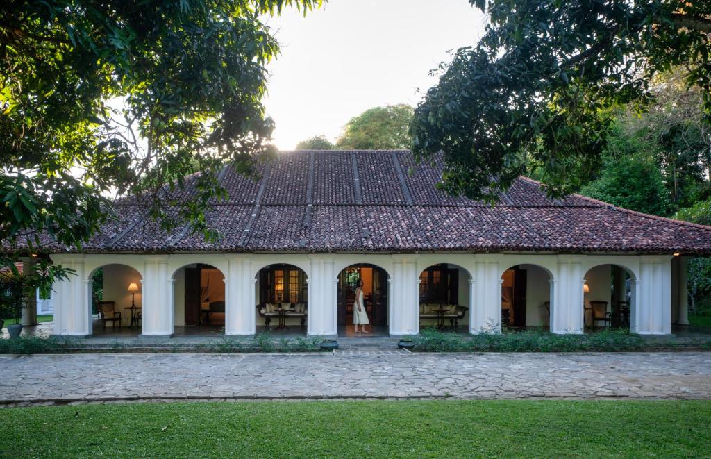 a woman stands in front of a building at Adigars Manor Kandy - A Boutique Heritage Hotel Built in 1804 in Kandy