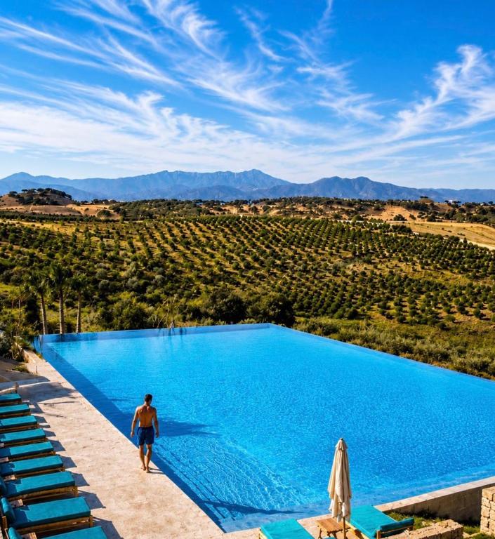 a man walking by a swimming pool in a vineyard at Kaha Lak in Douar Aguergour