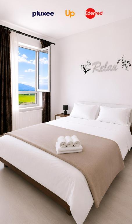 a bedroom with a large white bed with towels on it at Brasov Altipiani Apartments in Braşov