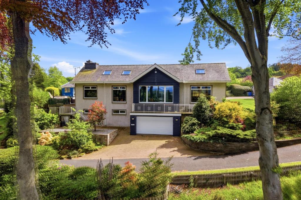 a house with a garage and trees at Five Marches - Poolside Stays with Stunning Views in Angus