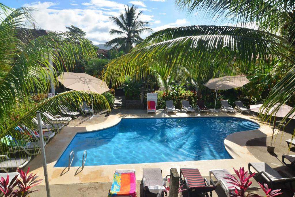 una gran piscina con sillas y sombrillas en Hotel Pochote Grande, en Jacó