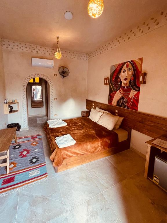 a bedroom with a bed with a painting of a woman at SiwaTu Lodge in Siwa