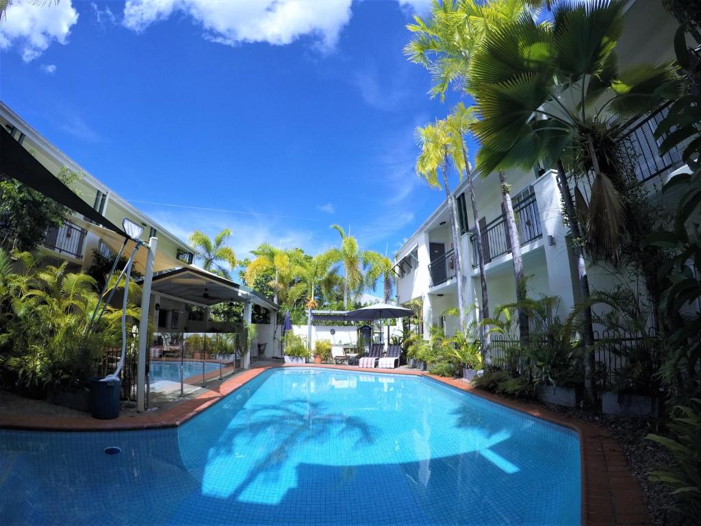 a swimming pool in front of a building with palm trees at Crystal Garden Resort & Restaurant in Cairns