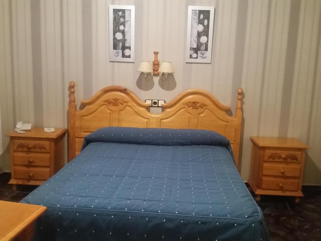 1 dormitorio con 1 cama azul y 2 mesitas de noche en Hotel Guadalquivir, en Cazorla