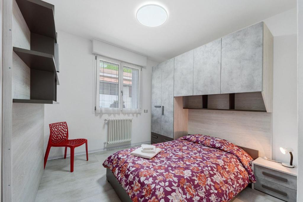 a bedroom with a bed and a red chair at Casa Cortina in Domodossola