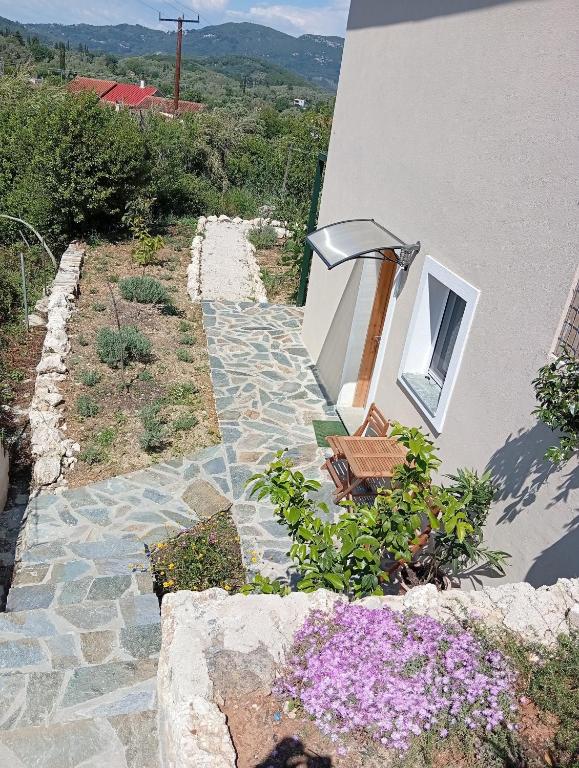 a stone walkway next to a building with flowers at Redon Marias House 1 in Ágios Matthaíos