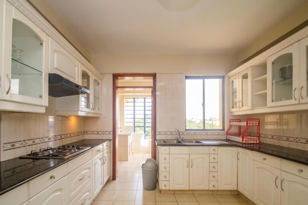 a kitchen with white cabinets and black counter tops at Legacy Homes in Nairobi