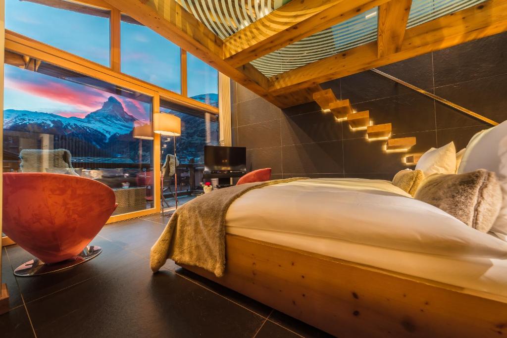 a bedroom with a large bed and a large window at Hotel Bellerive in Zermatt