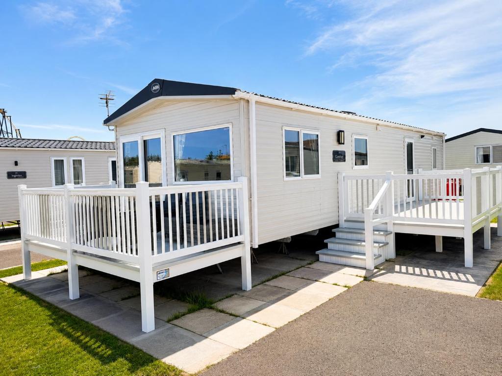 a white tiny house with two white decks at Hardys Caravan Park in Ingoldmells