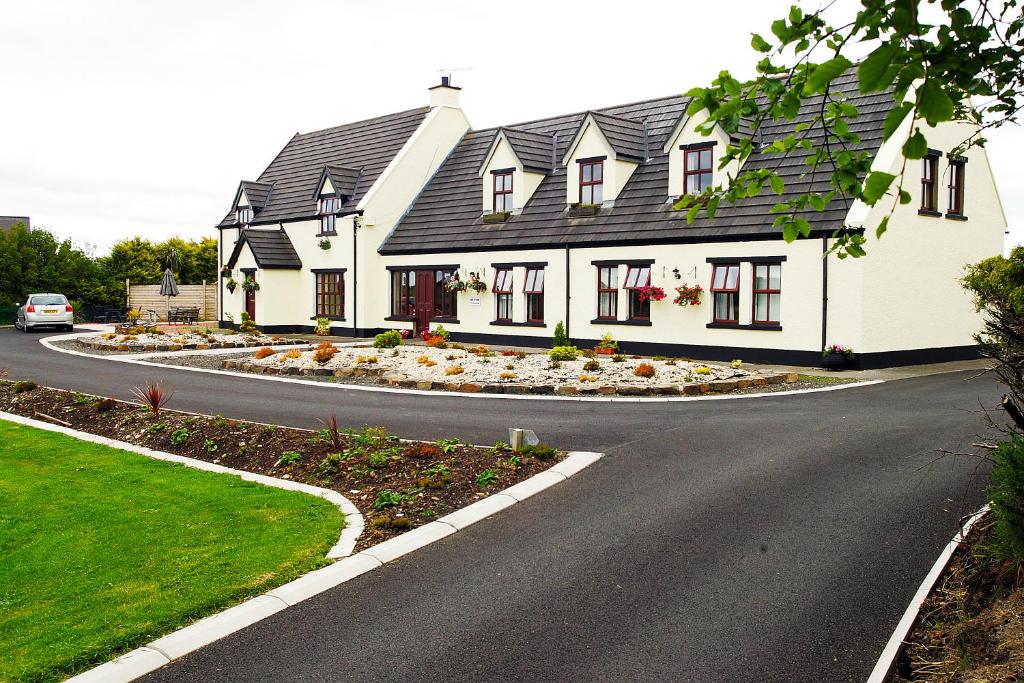 a large white house with a circular driveway at Glenmore House in Ballycastle