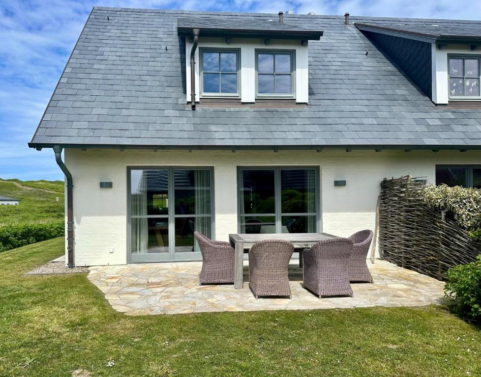 a patio with a table and chairs in front of a house at Strandhaus in Rantum