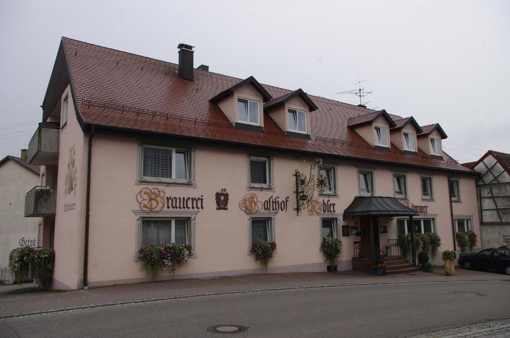 a white building with a red roof on a street at Brauereigasthof ADLER in Herbertingen