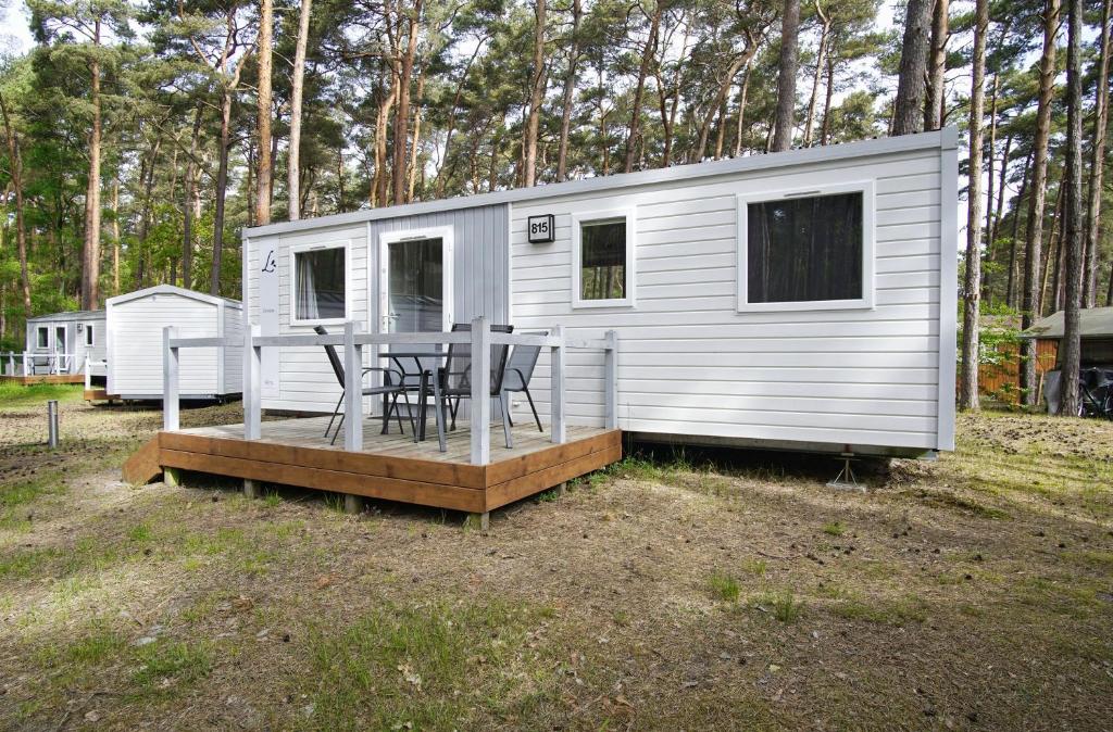 a white tiny house with a table and chairs on a deck at Tiny Chalet Nr 815 in Göhren