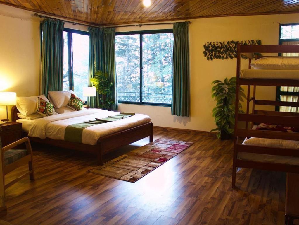 a bedroom with a bed and a couch and windows at Umda Hotel in Nathia Gali