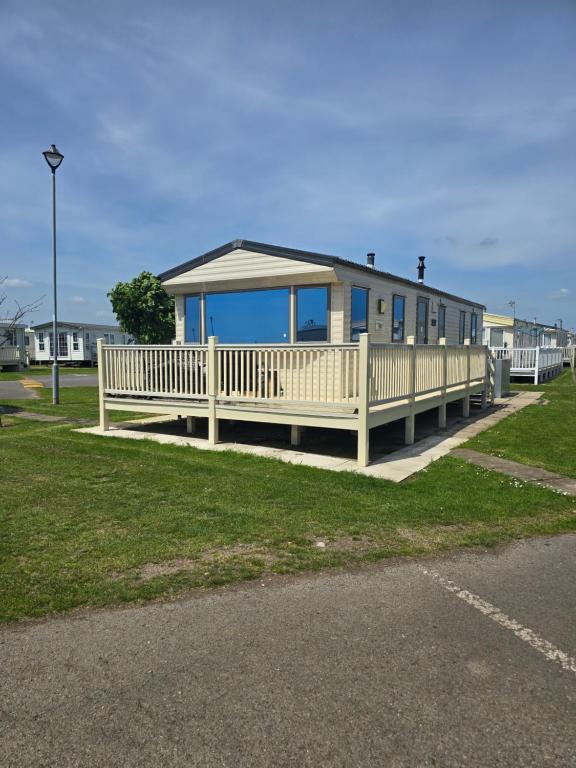 a house with a porch and a white fence at Chasing The Dream k52, Ingoldmells, FREE WIFI in Ingoldmells