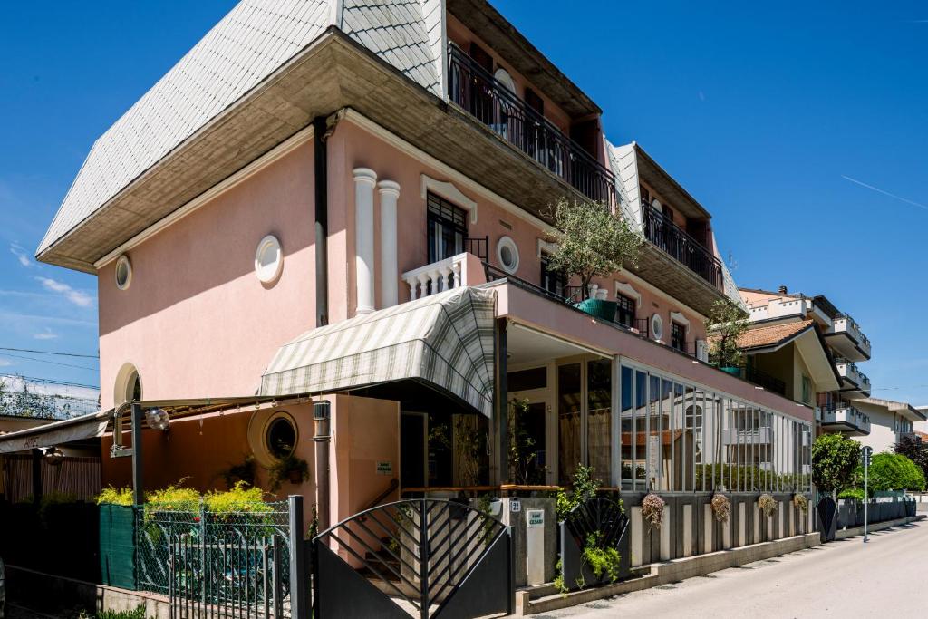 a pink building with a balcony on a street at Hotel Cesari in Rimini