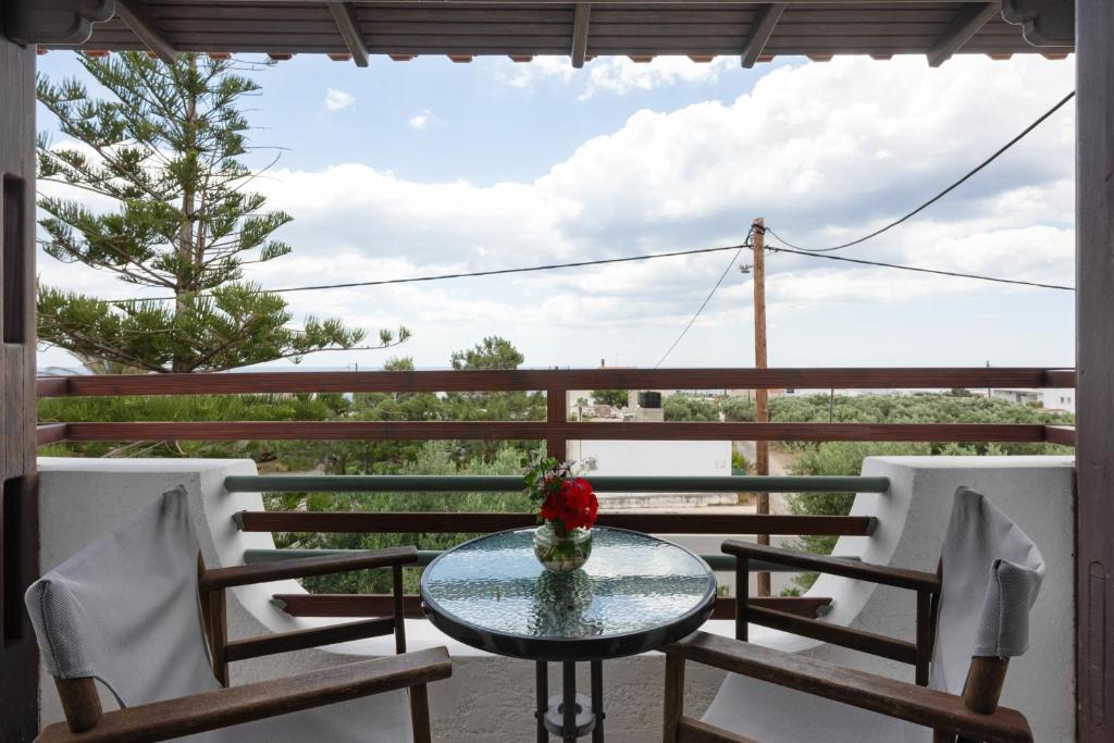 a glass table with a vase of flowers on a balcony at Apartment with sea view - Creta in Ferma