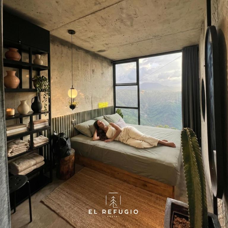 a woman laying on a bed in a room with a window at Cabaña el Refugio Buenavista in Buenavista