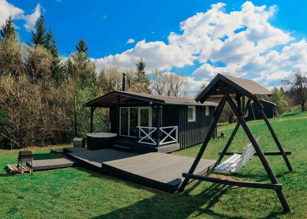 a small cabin with a porch and a swing at Trobelė miške in Palazdžiai