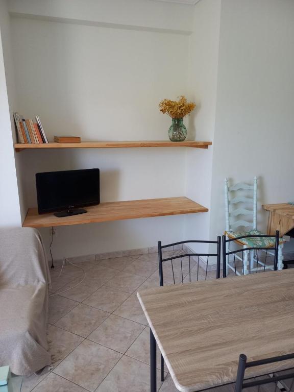 a living room with a table and a tv on a wall at Green House Schinias in Káto Soúlion