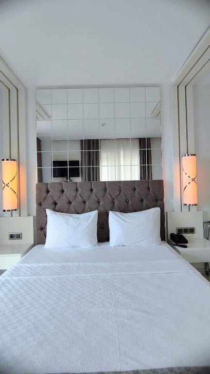 a bedroom with a large white bed with two pillows at Çözel Sare Hotel in Güzelçamlı