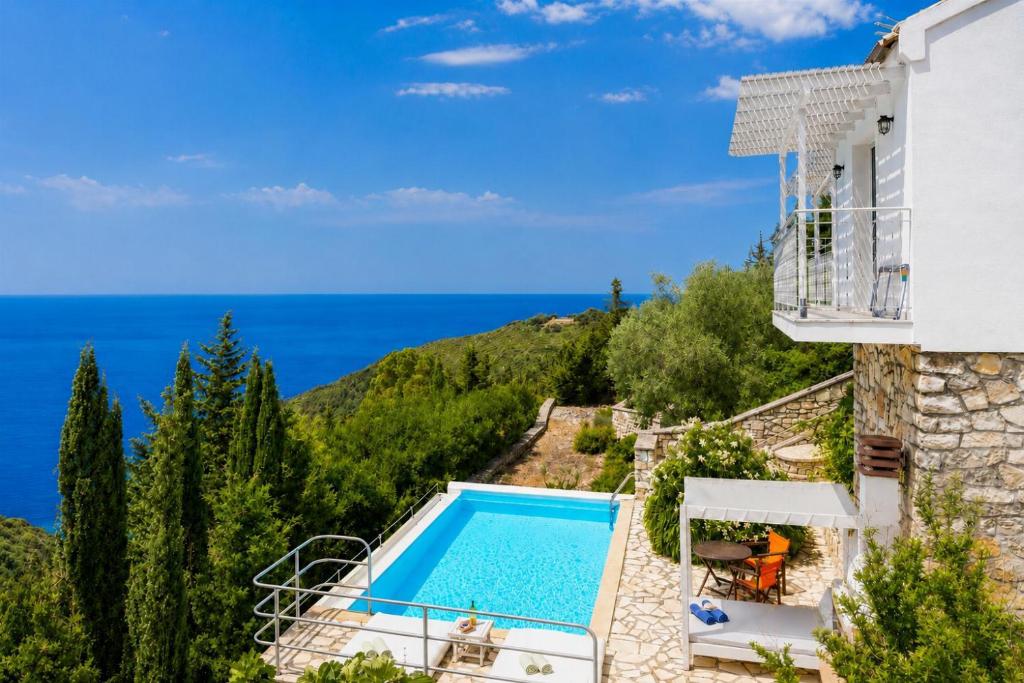 a villa with a swimming pool and a view of the ocean at Villa Bougainvillea in Vlachopoulátika