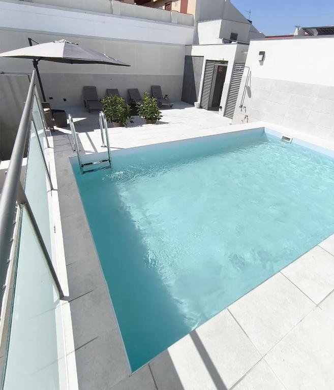 a blue swimming pool with an umbrella and a chair at HOTEL BESTPRICE Maragall in Barcelona