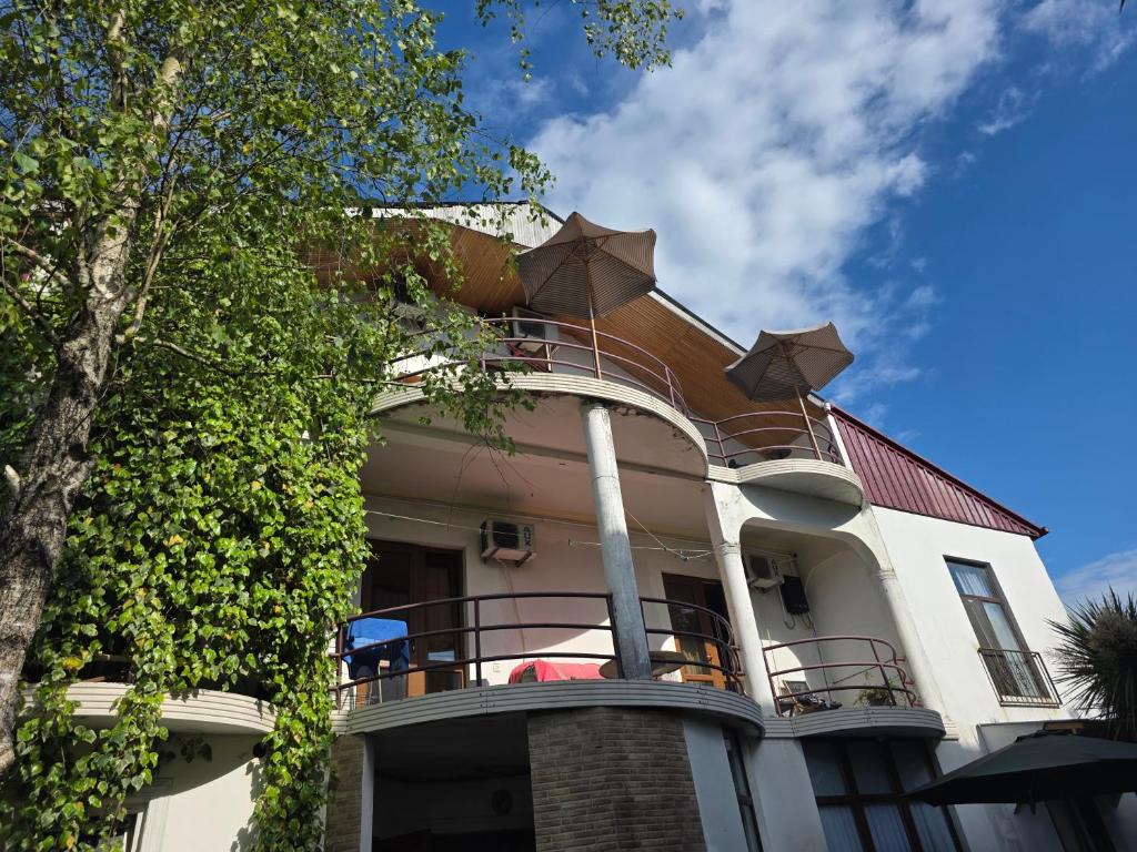 a large white house with a balcony on top of it at Merabi Guest House in Makhinjauri