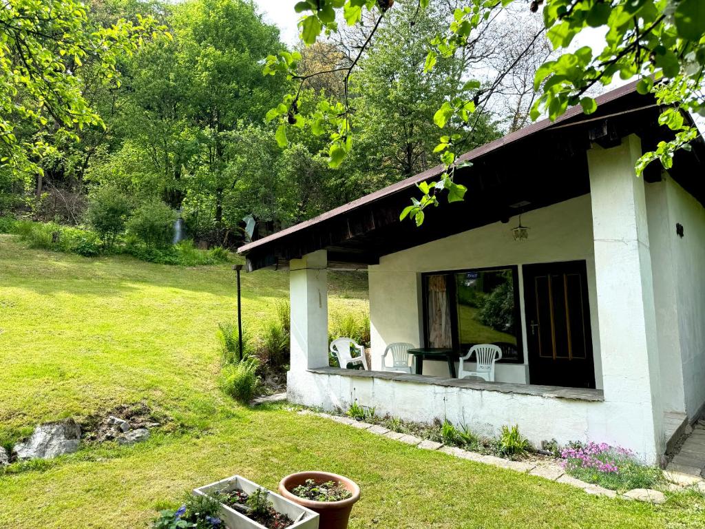 a house with a porch with two chairs in a yard at Chata Lesní Vyhlídka in Splzov