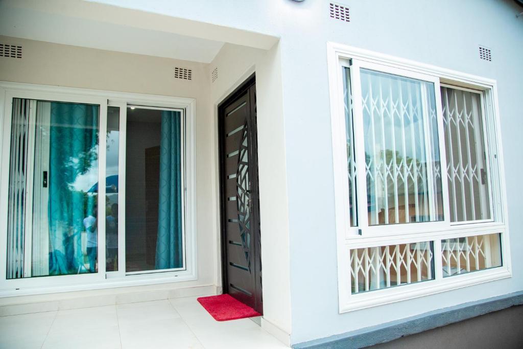 a white house with a black door and windows at LYYN Apartments in Chipata