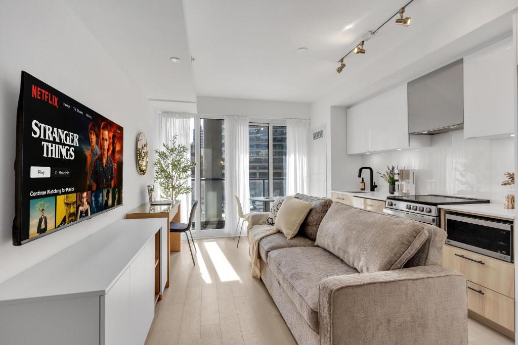 a living room with a couch and a kitchen at Work-Friendly 1BR Suite Steps to Eaton Centre in Toronto