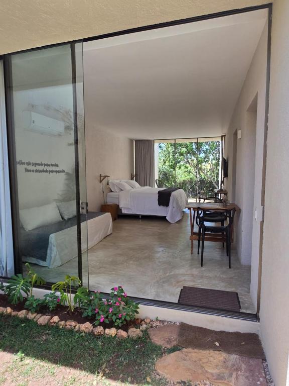 a room with a bed and a glass window at Statera Host - Pousada de Bem-Estar in Alto Paraíso de Goiás