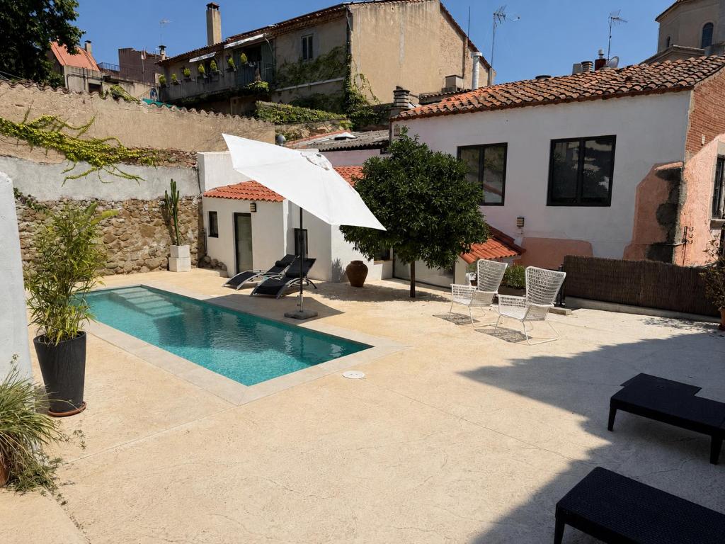 a swimming pool with a white umbrella and chairs at Costa Maresme, Barcelona ,Valentinos House & Pool in Vilassar de Dalt