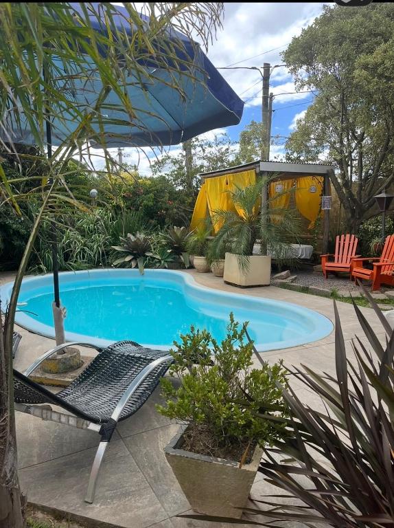 a swimming pool with a chair and an umbrella at Casa en Chuy in Chuy