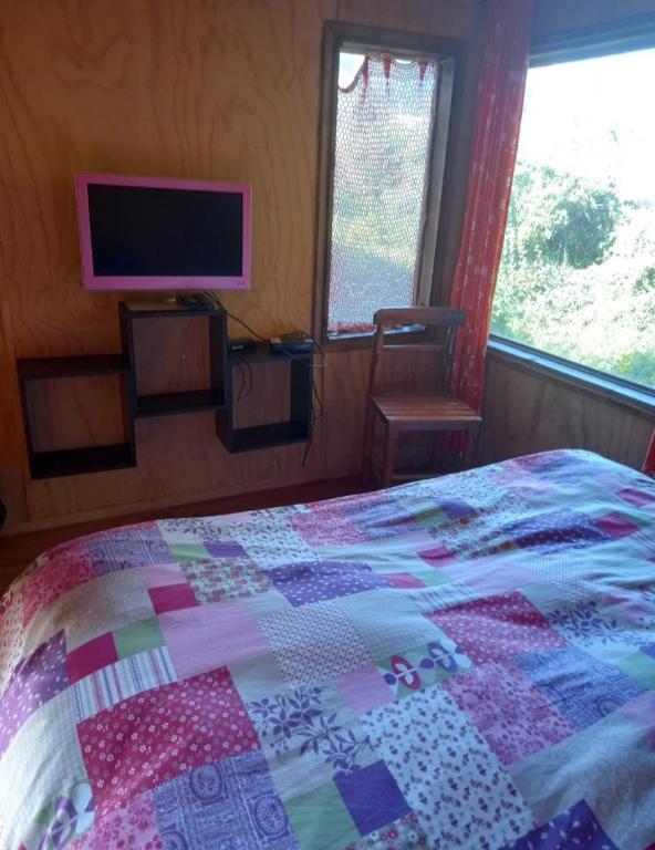 a bedroom with a bed with a quilt on it at Cabañita en la Isla in Isla Negra