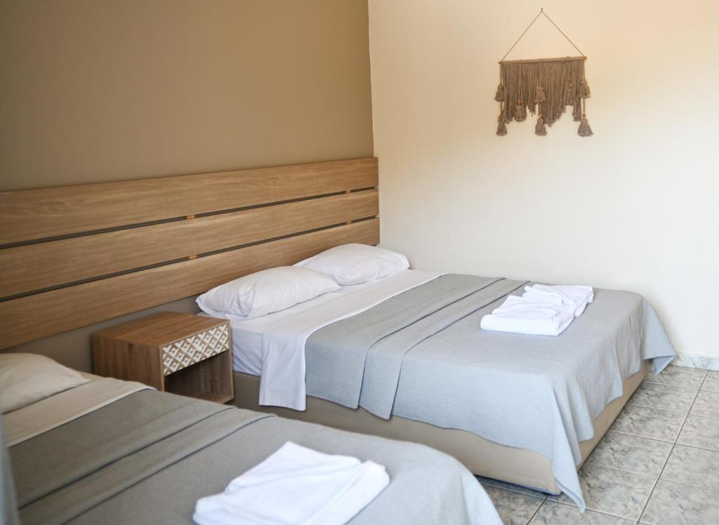 two beds in a hotel room with white sheets at Tota Marinou in Agioi Apostoli