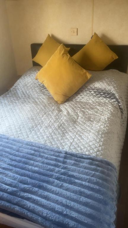 a bed with yellow pillows and a blue blanket at The Colorado van in Rhyl