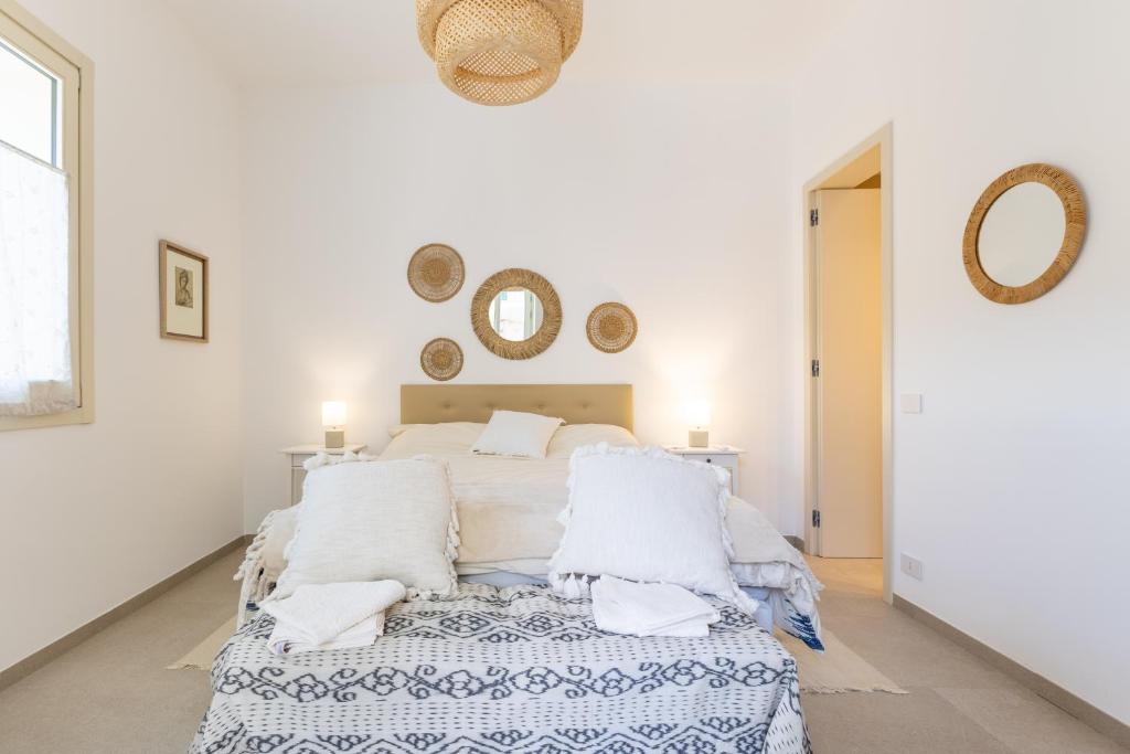 a white bedroom with a bed and mirrors on the wall at la perla sul mare in Sampieri