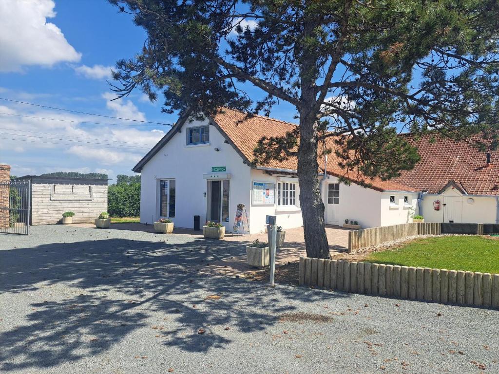 a white house with a tree in the driveway at Camping Les 2 Plages in Quend