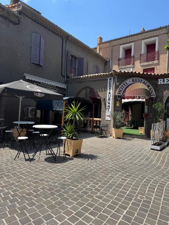 an outdoor patio with tables and umbrellas on a street at La Galiote in Agde